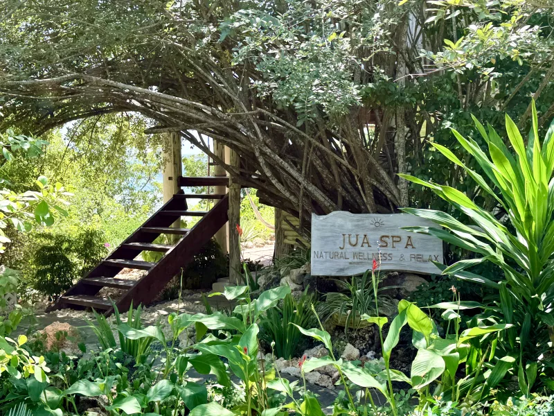 The garden steps up to Jua Spa, the spa sign set among tropical planting